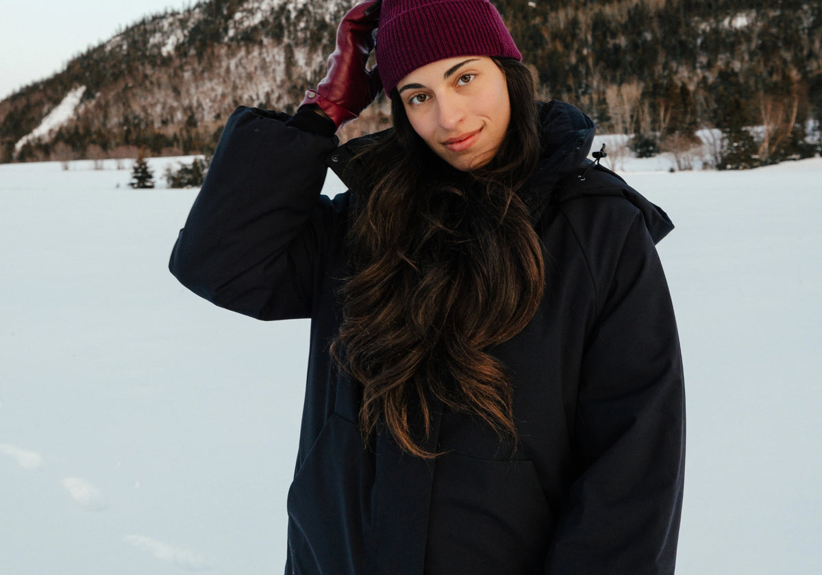 Femme portant le manteau d'hiver noir Tofino dans la neige